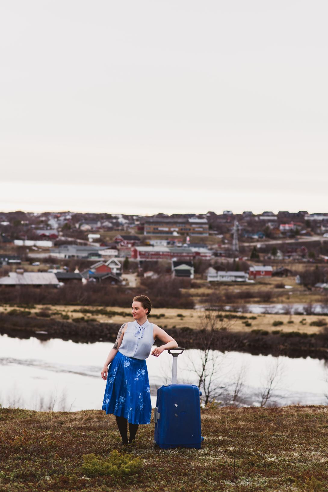 A woman with a travel bag standing by the river